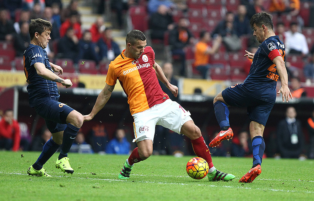 Lukas Podolski (Galatasaray) in Aktion gegen Ugur Ucar (L) und Emre Belozoglu (Beide Basaksehir) im Süper Lig Spiel Galatasaray gegen Basaksehir in der Turk Telekom Arena in Istanbul am 6. Februar 2016. Endergebnis: 3:3