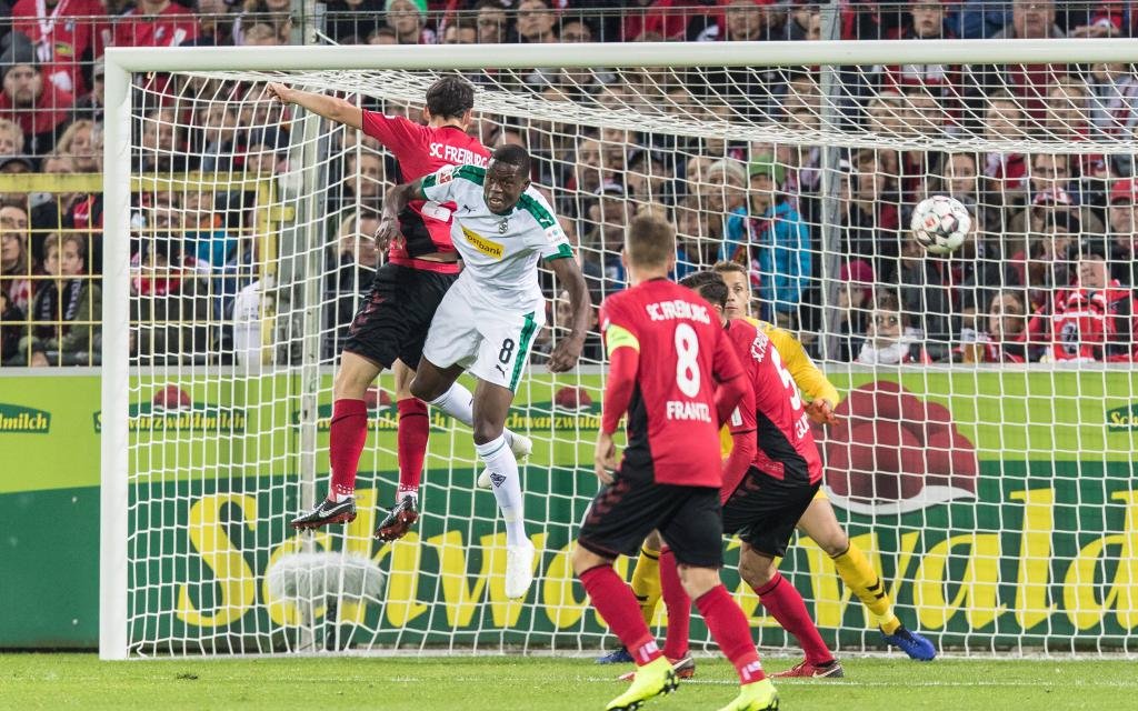 Kopfballduell zwischen Nicolas Hoefler (SC Freiburg 27) und Denis Zakaria (Borussia Moenchengladbach, 8) vor Freiburger Tor