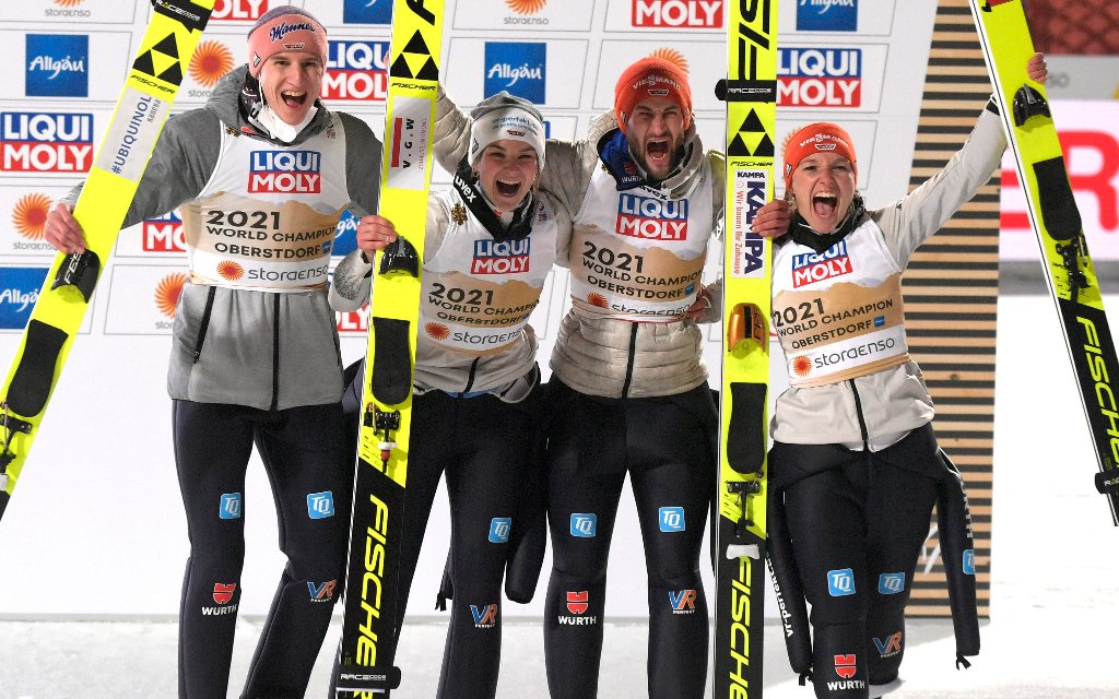 Nordische SKI WM Oberstdorf 2021, Oberstdorf im Allgäu, Skispringen Mixed, auf der 106m Schanze in der Erdinger Arena. v.l. Karl Geiger GER, Anna Rupprecht GER, Markus Eisenbichler GER und Katharina Althaus GER jubeln über den WM-Sieg.